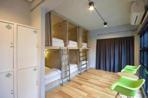 a room with bunk beds and a table and chairs at The Chatbox Silom Hostel in Bangkok