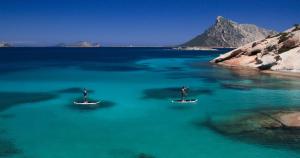 two people on surfboards in a body of water at Residence Hotel Lu Nibareddu in San Teodoro