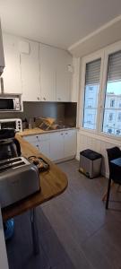 une cuisine avec des placards blancs et une table en bois dans l'établissement Sirius - SILS, à Caen