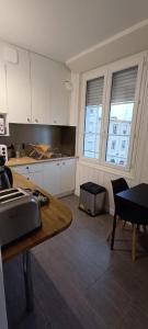 - une cuisine avec des placards blancs, une table et 2 fenêtres dans l'établissement Sirius - SILS, à Caen