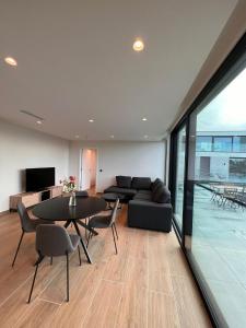 uma sala de estar com um sofá, uma mesa e cadeiras em ApartHotel Dénia em Lochristi