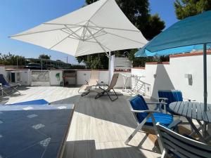 eine Terrasse mit Stühlen, einem Tisch und einem weißen Sonnenschirm in der Unterkunft Holiday Blue Oasis in Ascea