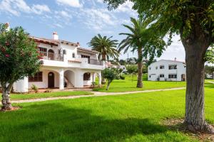 a large white house with palm trees in the yard at Apartamentos en Son Bou in Son Bou