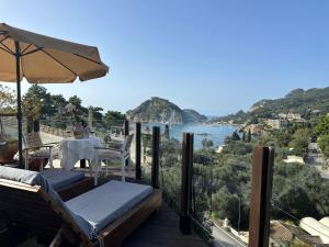 einen Balkon mit einem Tisch und einem Sonnenschirm in der Unterkunft Tango Studios in Paleokastritsa