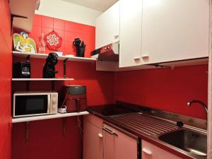 a red kitchen with a sink and a microwave at Hostdomus - La Via Lattea e Le Pleiadi in Cesana Torinese