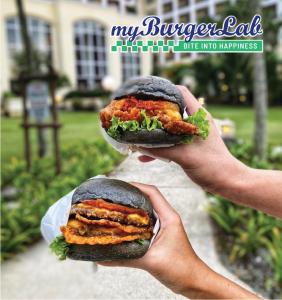 dos manos sosteniendo dos mitades de un sándwich en Bangi Resort Hotel, en Bangi
