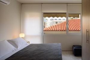 una camera da letto con finestra e vista su un tetto di ERMOU STREET APARTMENTs ad Atene
