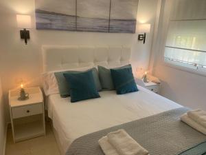 1 dormitorio con 1 cama blanca grande con almohadas azules en La Terraza del Campo de golf Playa Piscina y parking gratuito en Torre de Benagalbón