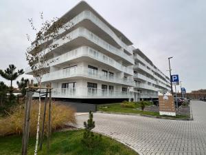 un edificio de apartamentos blanco con aparcamiento en Polanki AQUA Premium Class by MS Pro Apartamenty en Kołobrzeg