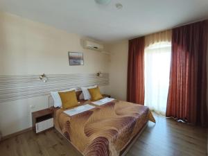 a hotel room with a large bed with yellow pillows at Семеен Хотел Детелини in Primorsko