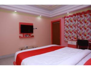 Hotel Swasti Deep, Tripura في آغارتالا: غرفة نوم مع سرير وتلفزيون على الحائط