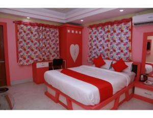 a bedroom with a large bed with red walls at Hotel Swasti Deep, Tripura in Agartala