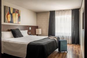 une chambre d'hôtel avec un lit et une valise dans l'établissement ALEGRIA President, à Andorre-la-Vieille