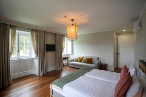- une chambre avec un grand lit et un canapé dans l'établissement Casa Portuguesa - Charming House, à Ponta Delgada