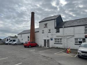 a brick building with a chimney and cars parked in a parking lot at The White Lion Hotel in Bridgend