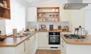 uma cozinha com armários brancos e um forno com placa de fogão em Newperran Holiday Park em Newquay