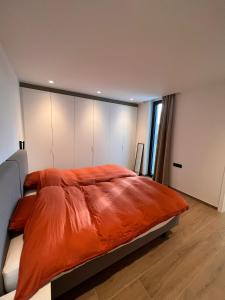 a bedroom with a large bed with an orange comforter at ApartHotel Dénia in Lochristi