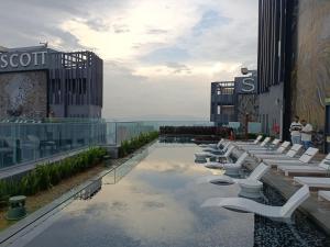 吉隆坡的住宿－Star KLCC By Cozy White，一座带白色躺椅的建筑的顶部游泳池