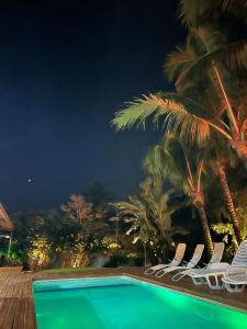 a pool with chairs and palm trees at night at Moana Ilhabela in Ilhabela