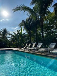 un grupo de sillas y una piscina con palmeras en Moana Ilhabela en Ilhabela