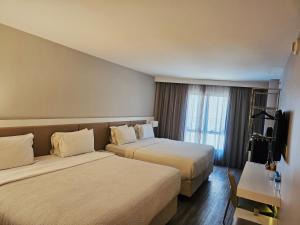 a hotel room with two beds and a television at Radisson Rio de Janeiro Barra in Rio de Janeiro