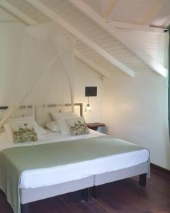 Caraib'Bay Hotel في ديساي: غرفة نوم مع سرير أبيض كبير في غرفة