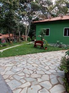 um pátio de pedra em frente a uma casa verde com um banco em Pousada Da Mata em Pirenópolis