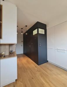 une cuisine avec une porte noire et des placards blancs dans l'établissement Studio Centre Douai - Wifi, à Douai
