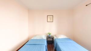 two beds in a room with blue sheets at LIDO CASA BRANCA in Funchal