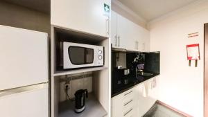 a white kitchen with a microwave on a shelf at LIDO CASA BRANCA in Funchal