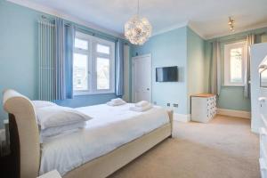 a blue bedroom with a large bed and a chandelier at Pass the Keys Large house Leigh Sea views in Southend-on-Sea