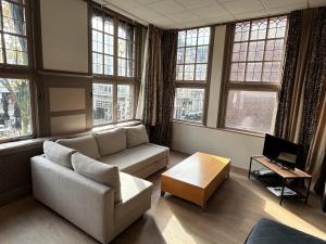 Stylish Studio S1, City Centre Dordrecht في دوردريشت: غرفة معيشة مع أريكة وطاولة ونوافذ