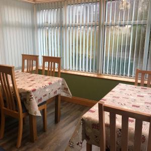 two tables and chairs in a room with windows at Number 12 Self Catering in Portree