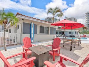 a patio with red chairs and a table and umbrellas at Siesta By The Beach in Pompano Beach