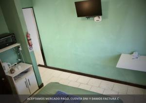 baño con pared verde y TV en la pared en Habitación Tres Arroyos en Tres Arroyos