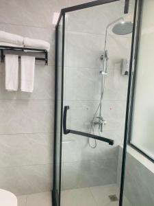 een douche met een glazen deur in de badkamer bij Zebulun Hotel in Lijiang