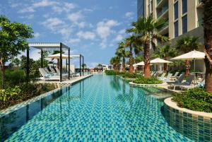 a swimming pool at a resort with chairs and umbrellas at DAMAC Maison Aykon City Dubai in Dubai