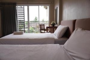 a hotel room with two beds and a window at Chompu Nakarin Apartment in Trang