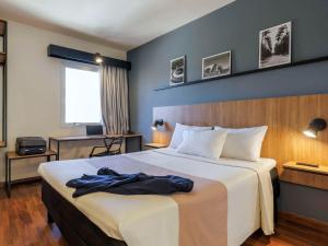 a bedroom with a large bed with a blue wall at ibis Belo Horizonte Liberdade in Belo Horizonte