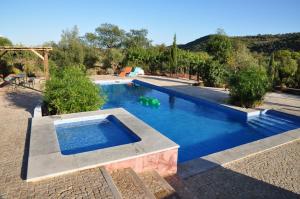 a swimming pool with blue water in a yard at Fazendinha - Tavira - Spacious and tranquil in Tavira
