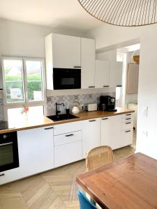 a white kitchen with white cabinets and a table at Charmante maison Cabourg in Cabourg