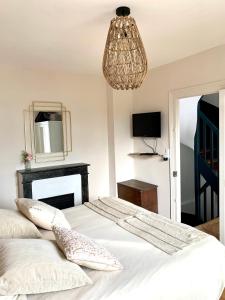 a bedroom with a bed with a mirror and a chandelier at Charmante maison Cabourg in Cabourg