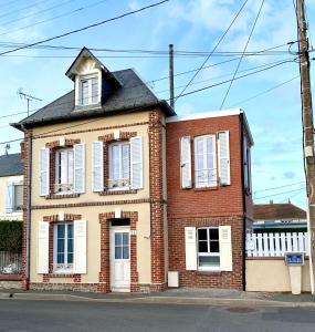 an old brick house with white shutters on a street at Charmante maison Cabourg in Cabourg