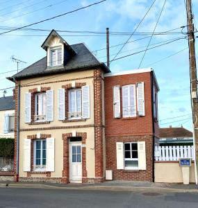 an old brick house with white shutters on a street at Charmante maison Cabourg in Cabourg