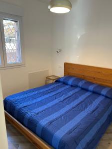 ein blaues Bett in einem weißen Zimmer mit Fenster in der Unterkunft Casa Marisa in Camporosso
