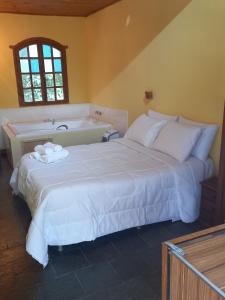 um quarto com uma cama grande e uma banheira em Cipó Hostel em Serra do Cipó