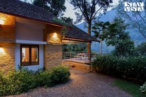 a house with a deck with a table on it at StayVista at Cave Song with Bonfire & Complimentary Breakfast in Idukki