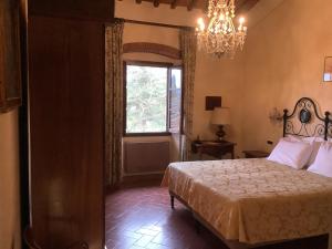 a bedroom with a bed and a window and a chandelier at Villa Rigacci Hotel in Reggello