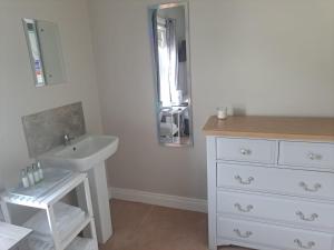 uma casa de banho branca com um lavatório e um espelho em New Lisnagalt Lodge em Coleraine