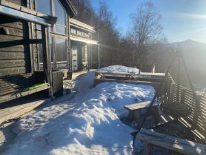 un porche cubierto de nieve de una casa con el sol brillando en Moderne hytte i Svandalen, Sauda - nær skisenter og natur, en Sauda